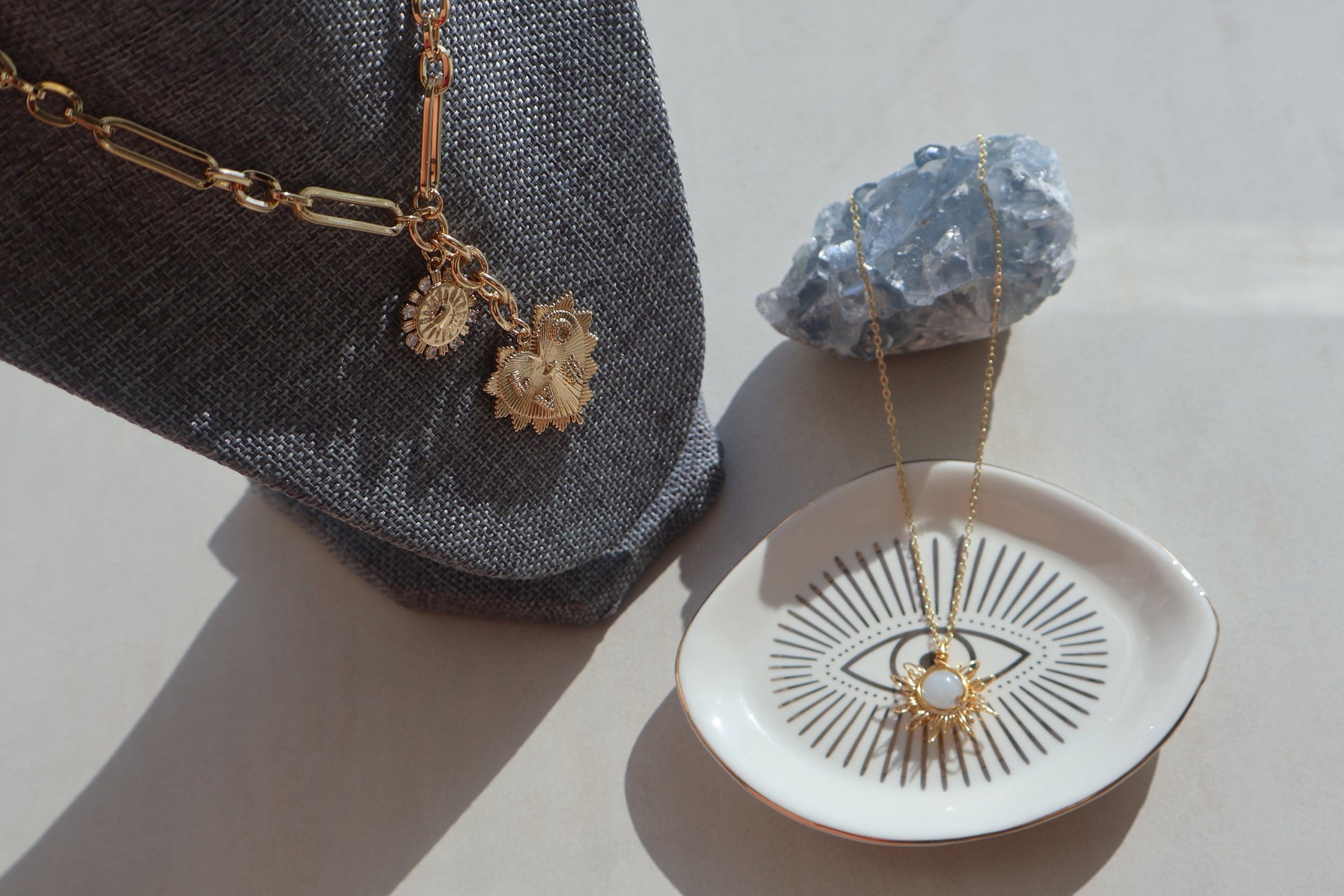 Gold Heart Love Necklace with sun pendant and cubic zirconia, displayed on fabric and dish.