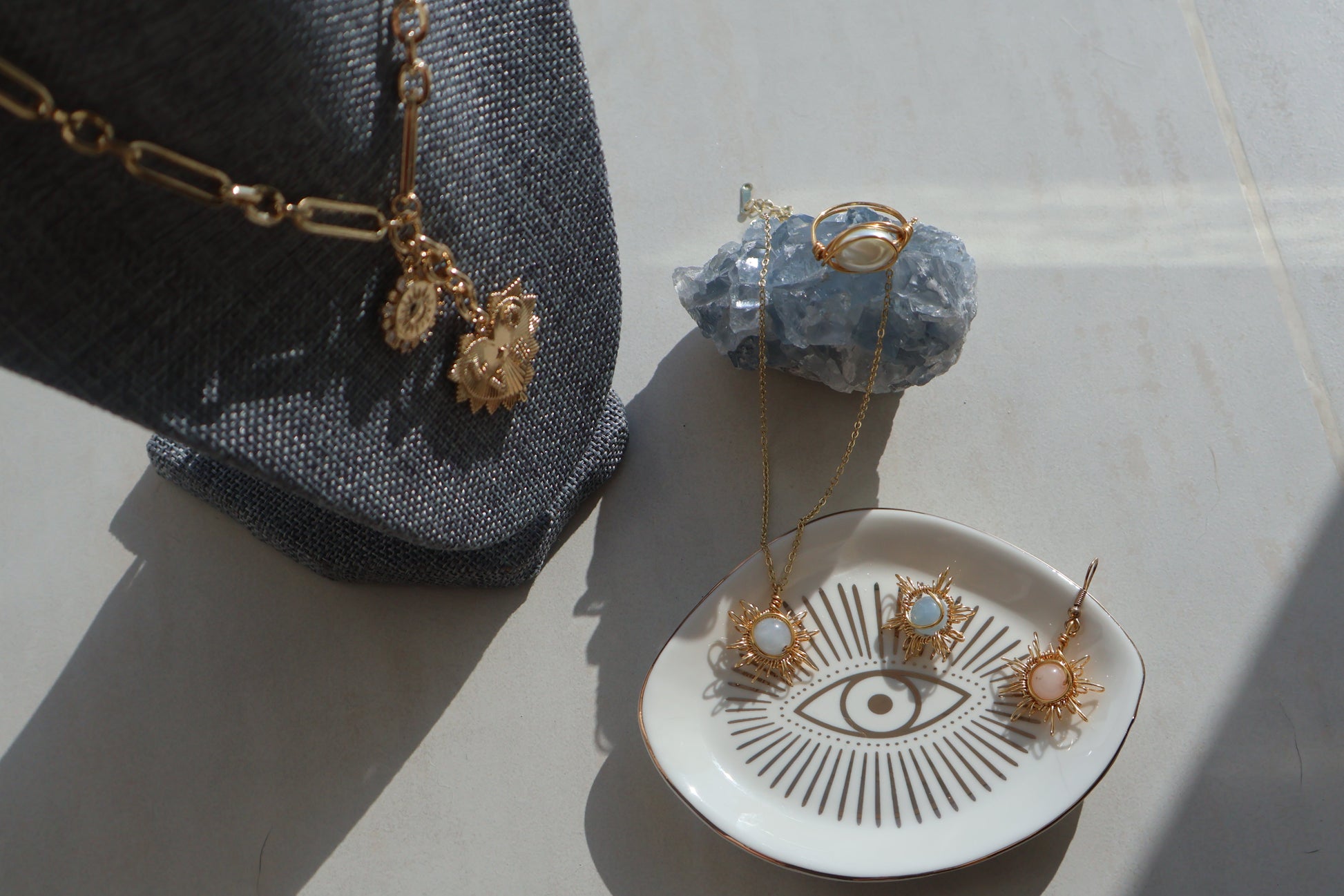 Gemstone Sun and Moon earrings with celestial motifs displayed on a decorative dish alongside matching jewelry pieces.