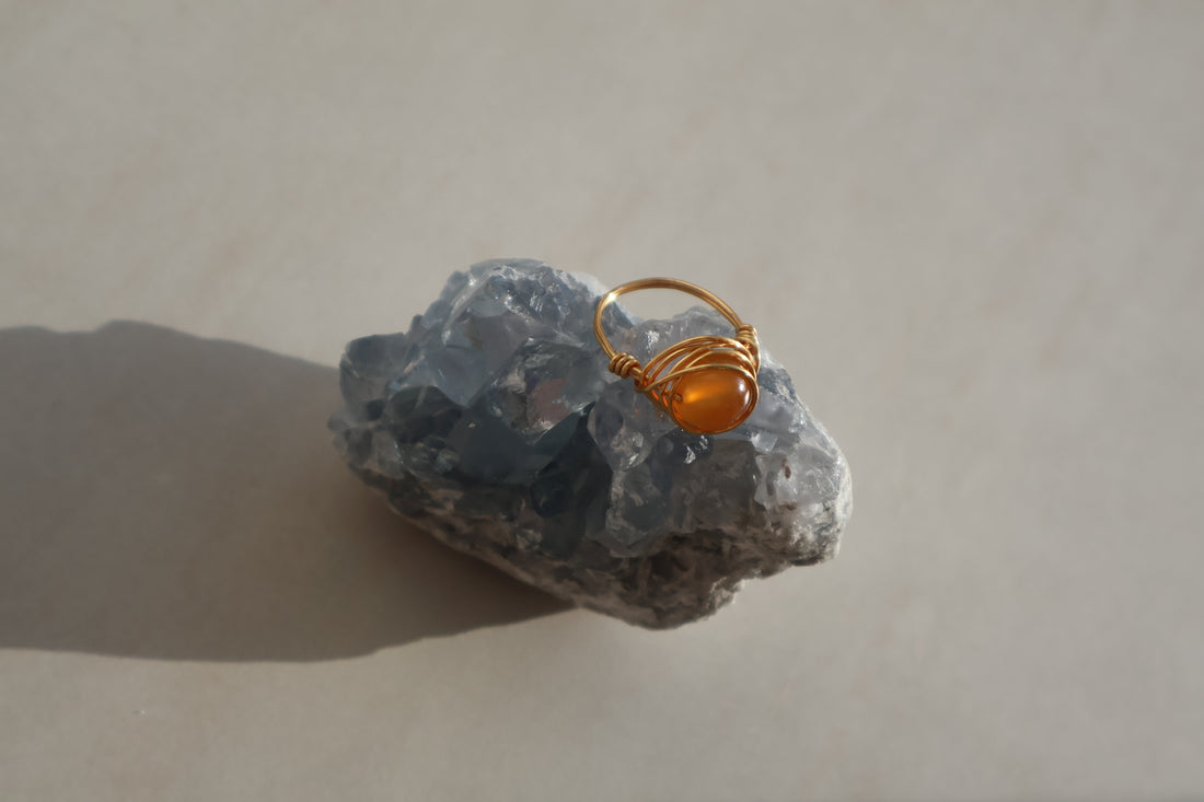 Amber Gemstone Ring with gold plated copper wire on a natural stone background.