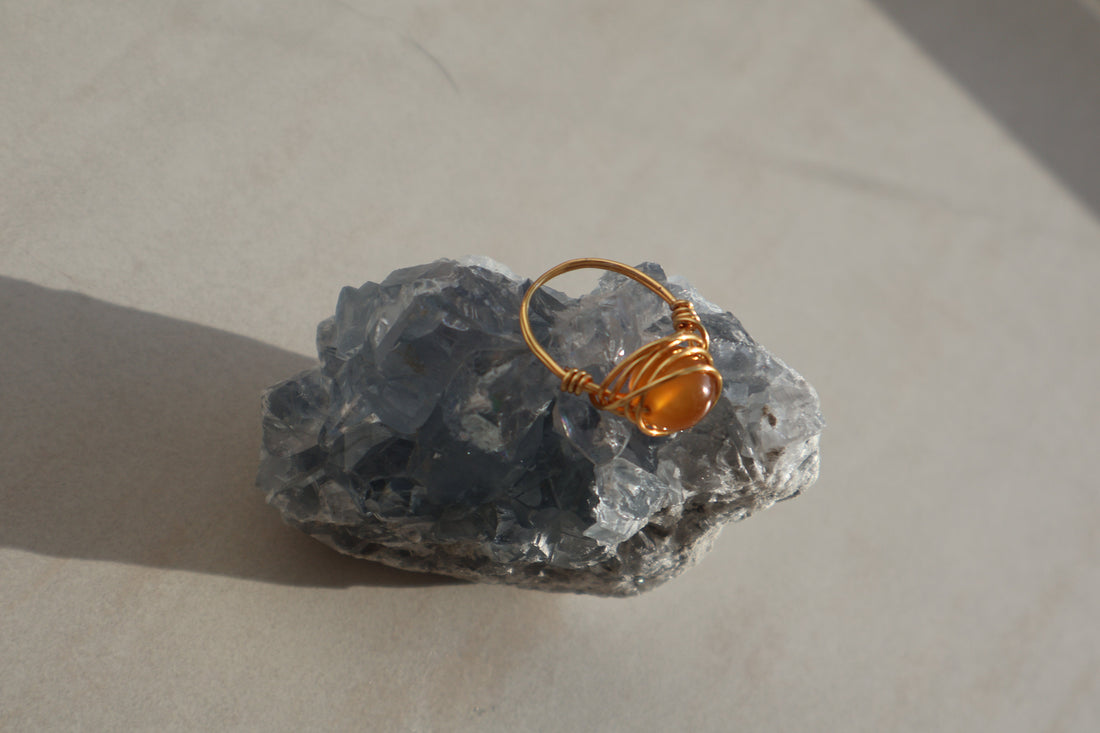 Amber Gemstone Ring with gold plated copper wire on a natural stone background.