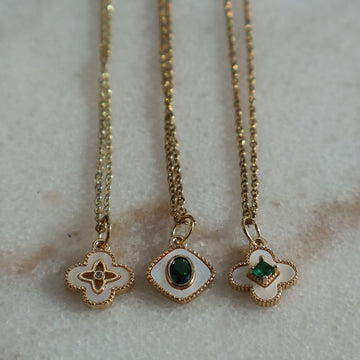 Gold necklace with pearl four leaf clover pendant on adjustable chain.