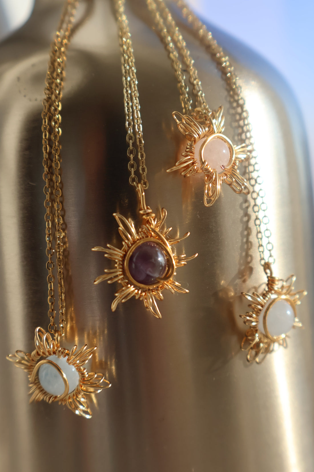 Sunburst Gemstone Necklace with intricate wire-wrapped sun design pendant on gold chains.