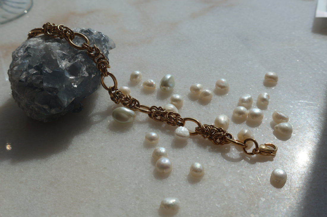 Vintage Gold Chain Bracelet with elegant design on marble surface surrounded by pearls.