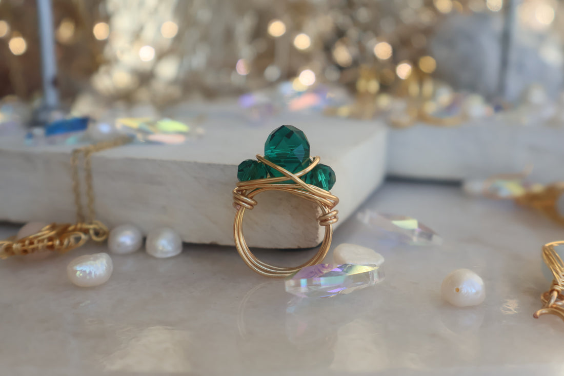 Gold Emerald Green Bead Ring with copper wire wrapping on marble background.